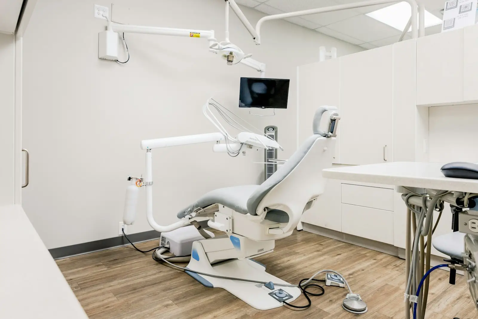 Sala di uno studio dentistico luminosa e ordinata, con la poltrona bianca e grigia pronta per il paziente